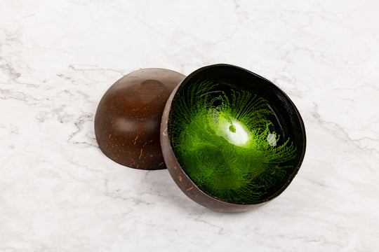 Green resin coconut bowl with textured surface inside, placed on a white marble surface