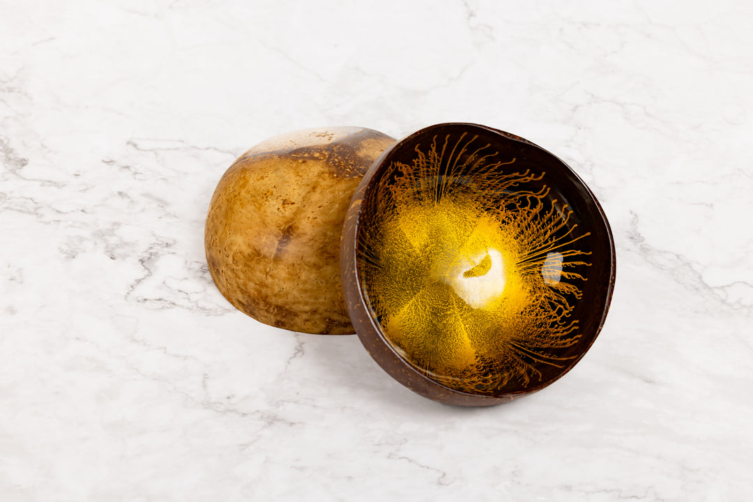 Coconut shell with gold resin inside on a white marble surface