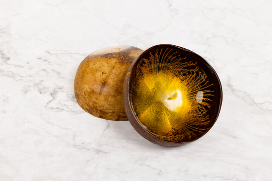 Coconut shell with gold resin inside on a white marble surface