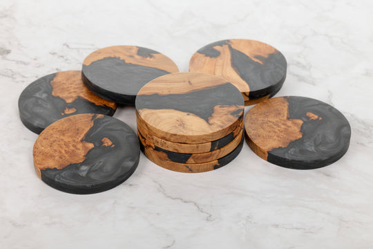 Set of round wooden coasters with black accents on a light gray surface