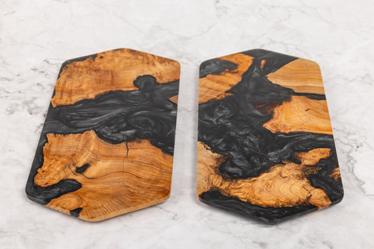 Two wooden coasters with black resin inlay on a light gray surface