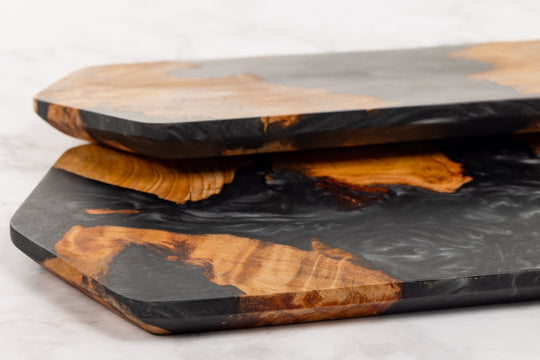 Set of wooden cutting boards with black resin inlay on a light background