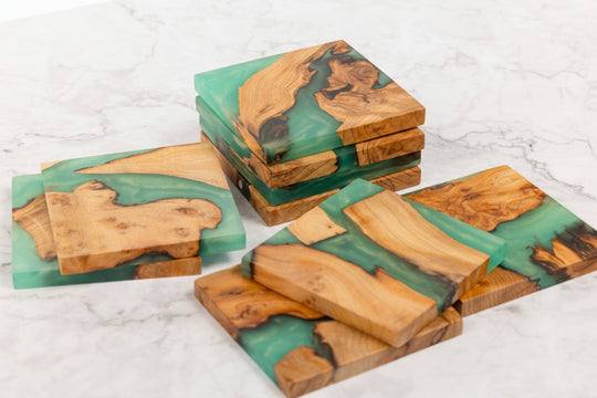 Wooden coasters with green resin on a white marble surface