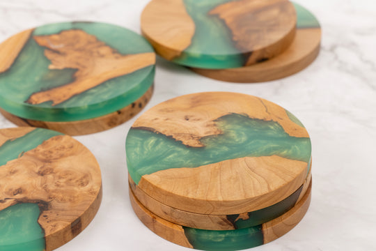Set of wooden coasters with green resin inlay on a white surface
