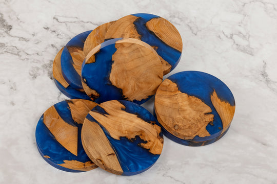 Set of wooden coasters with blue and brown design on a marble surface