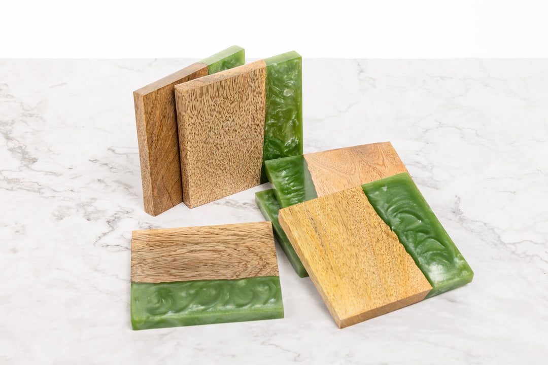 Set of wooden coasters with green accents on a marble surface