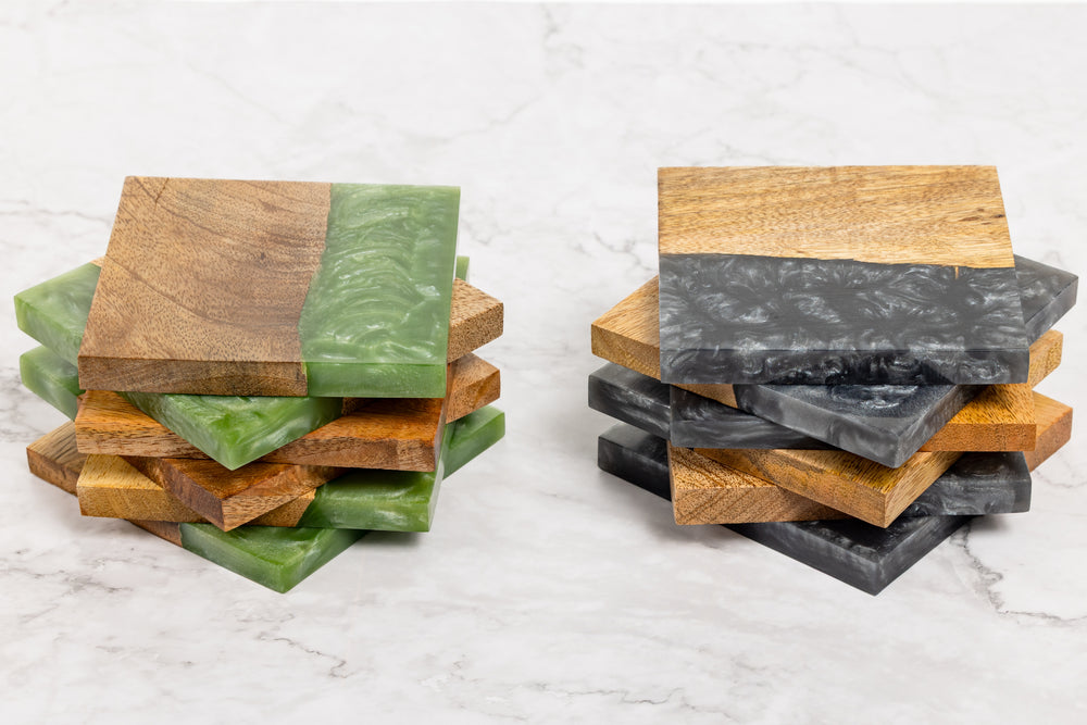 Stacks of wooden coasters with green and gray stone inserts on a marble surface