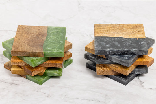Stacks of wooden coasters with green and gray stone inserts on a marble surface