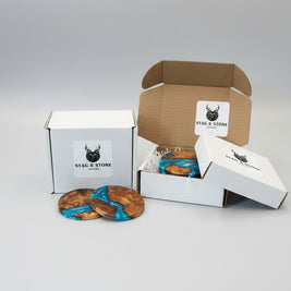 Wooden coasters with blue resin on a wooden surface, with 'Stag & Stone' branded box in the background.
