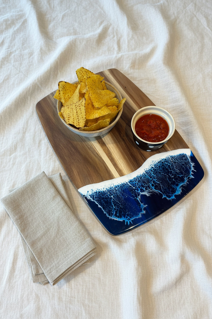 Bowl of tortilla chips with salsa on a decorative cutting board on a white surface