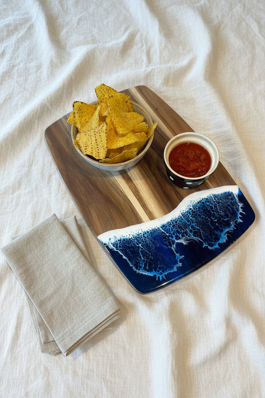 Bowl of tortilla chips with salsa on a decorative cutting board on a white surface