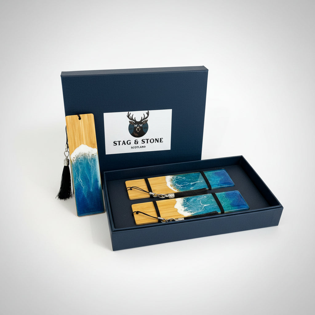 Stag & Stone Scotland gift set featuring a wooden bookmark with a black tassel and a blue-and-white wave design, displayed next to an open navy blue presentation box containing four matching rectangular coasters with a resin ocean wave pattern.