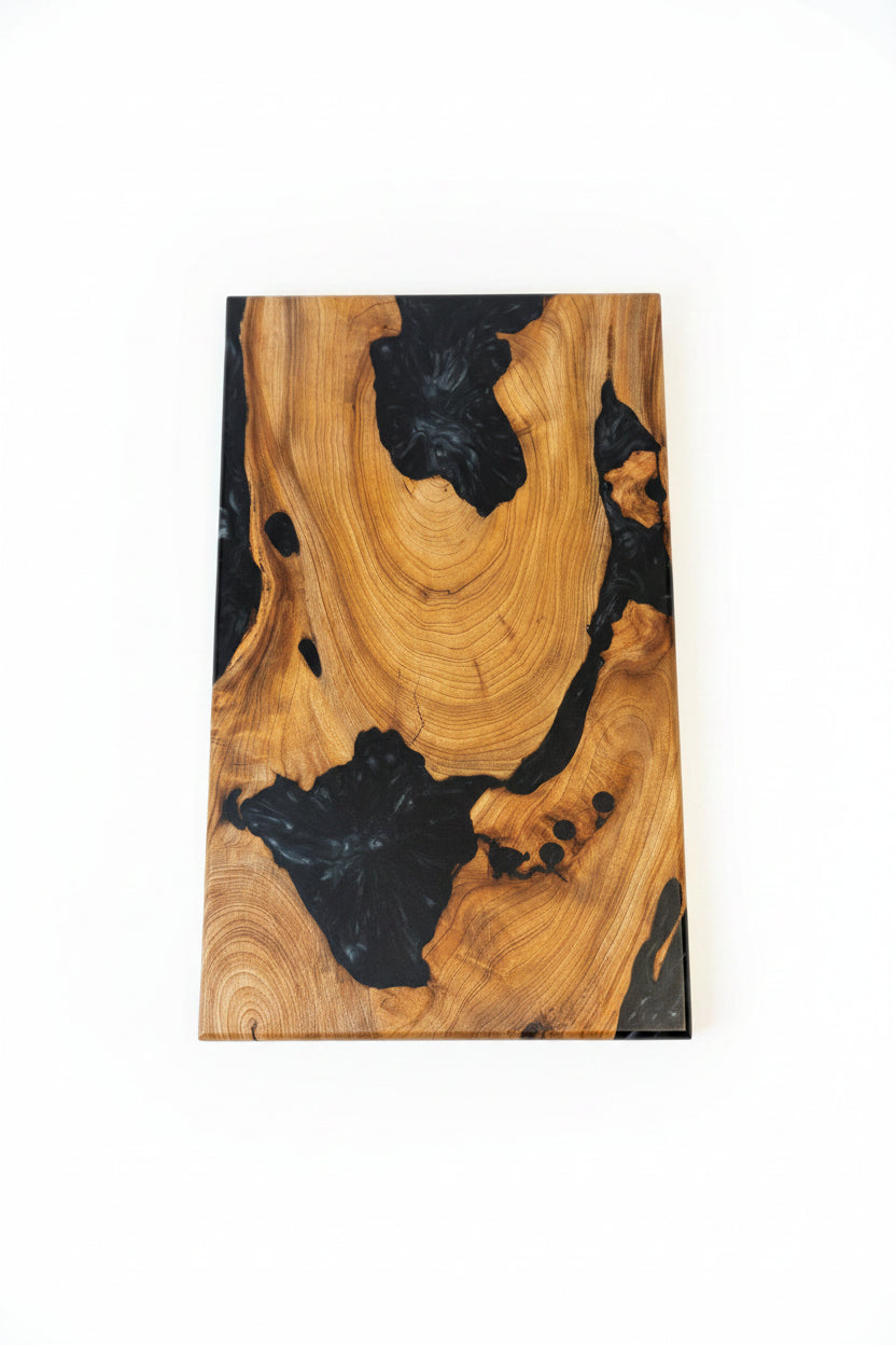 A rectangular wooden board with a live edge, featuring natural golden-brown wood grain and dramatic black resin inclusions, shown against a plain white background.