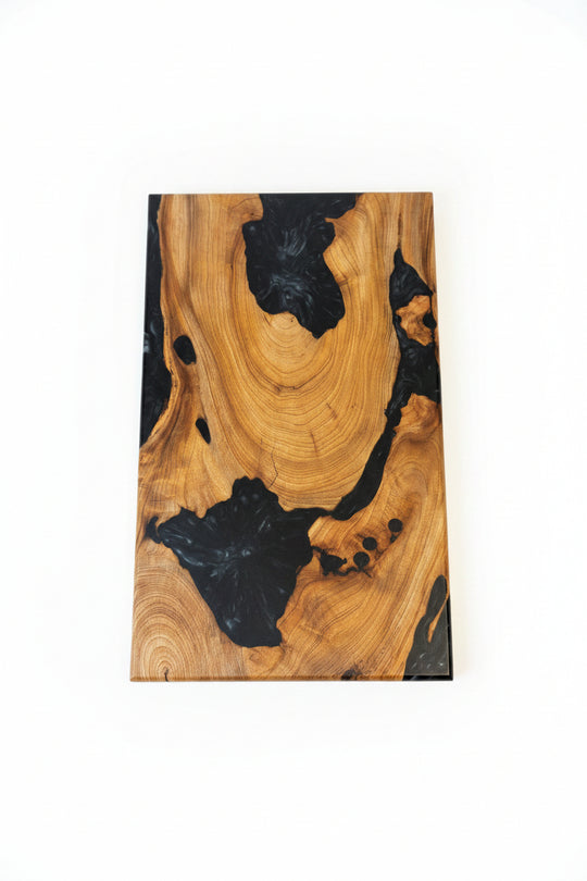 A rectangular wooden board with a live edge, featuring natural golden-brown wood grain and dramatic black resin inclusions, shown against a plain white background.