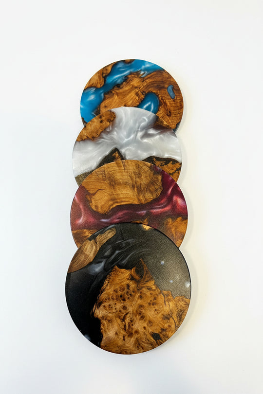 Four overlapping oval coasters with a glossy burl wood grain pattern in various colors including blue, white, gold, burgundy, and black, displayed on a clean white background.
