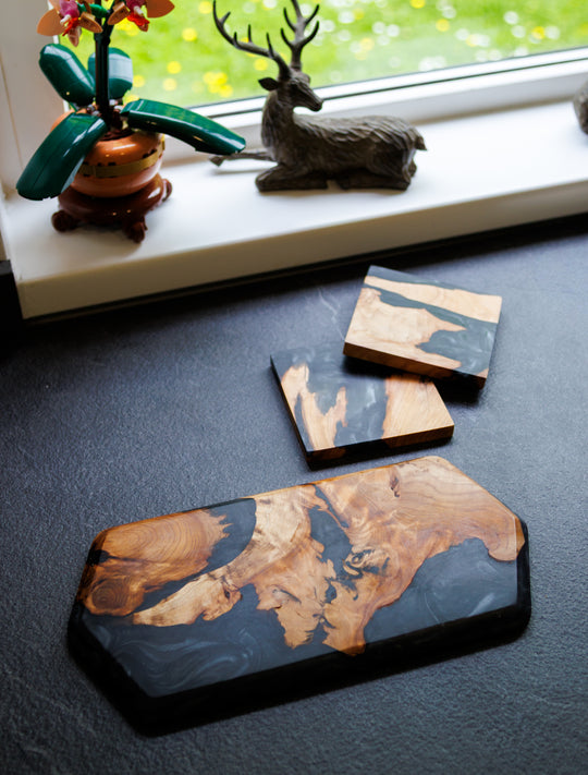 Wooden coasters on a dark surface with decorative items in the background