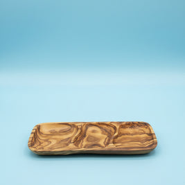 A rectangular wooden serving tray with a carved, swirling natural wood grain pattern, resting on a light brown wooden table.