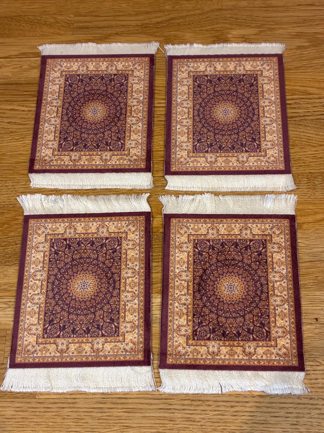 Four patterned rugs with tassels on a wooden surface