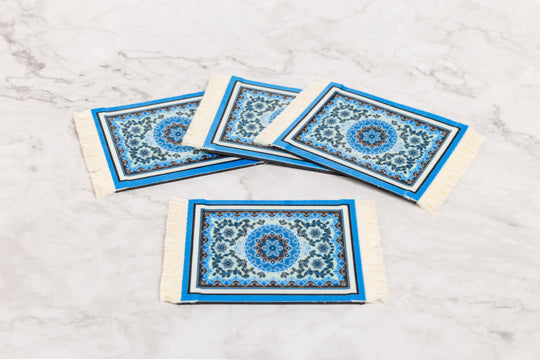 Four blue and white patterned coasters on a marble surface