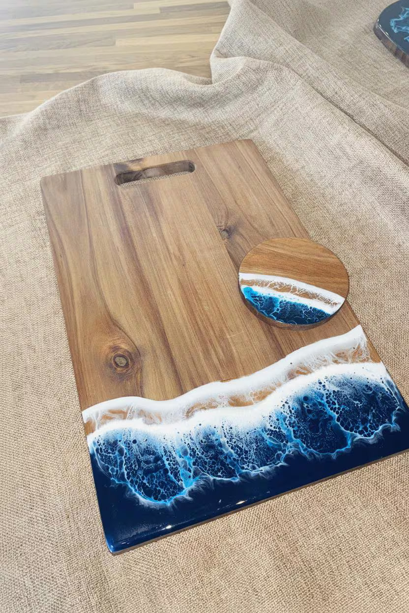 A wooden cutting board with a wave design in blue and white resin at the bottom, placed on a beige linen surface.