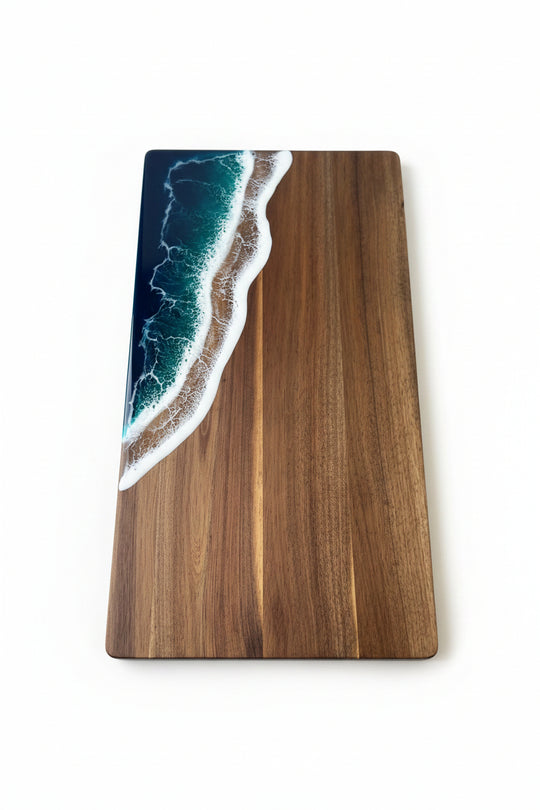 A rectangular wooden board or tray with a glossy dark brown wood grain finish and an embedded ocean wave design in the top-left corner, placed on a textured beige fabric surface.